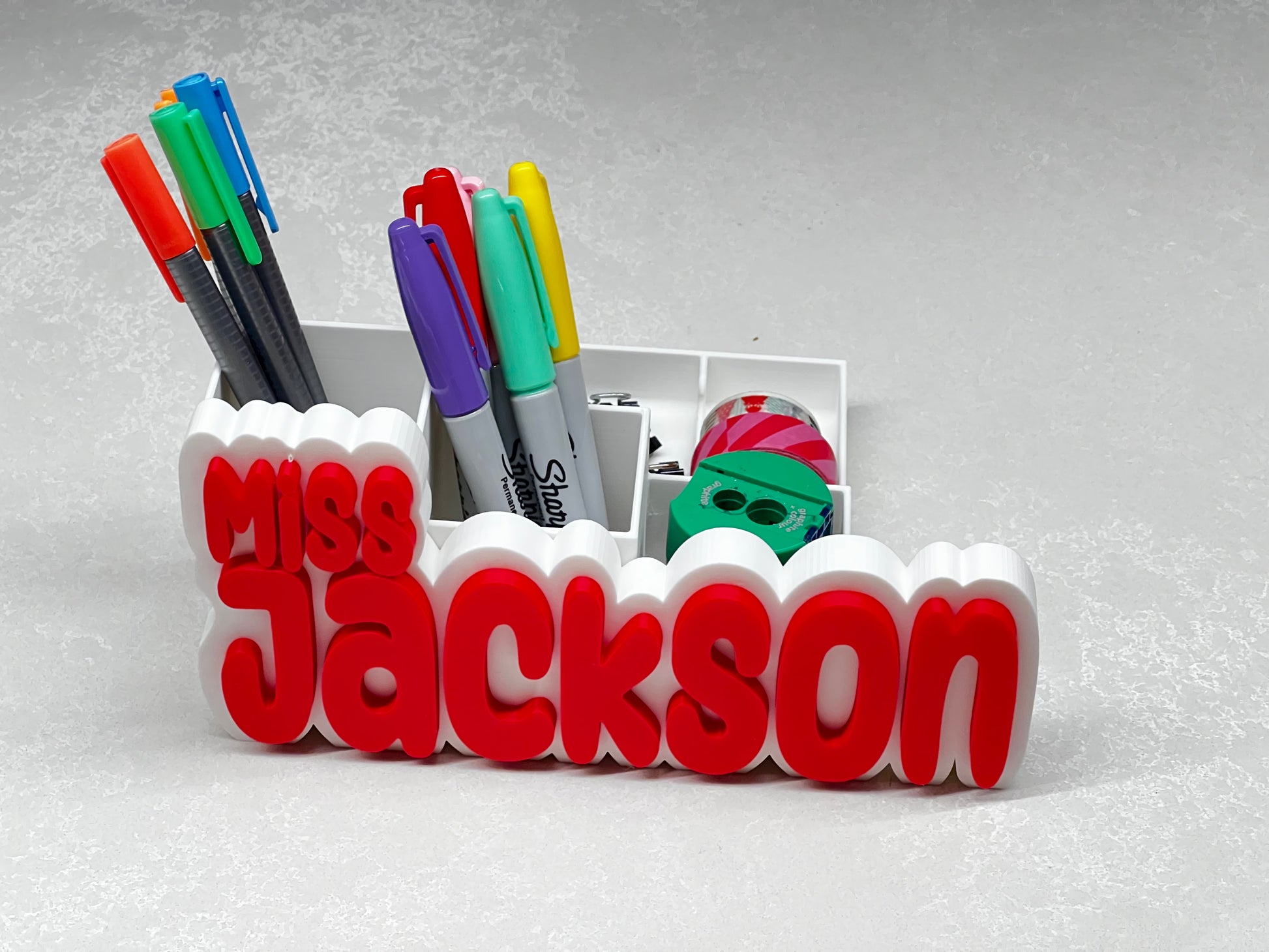 Desk organizer with stationery items and 'Miss Jackson' branding on a gray background